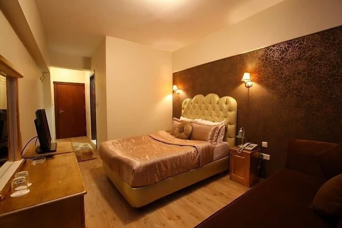 A hotel room with a large bed, bedside lamps, a wooden desk, and a mirror.