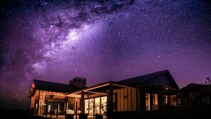A modern house with a large glass window area under a starry night sky. - Te Arai Lodge (Te Arai)