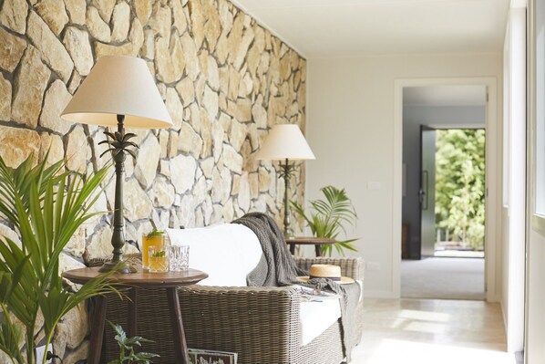 A cozy room with a stone wall, wicker furniture, and two lamps.