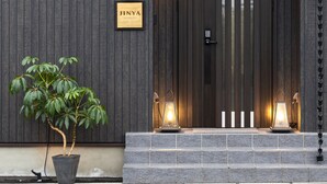 A building with a dark wooden facade, a sign reading "JINYA", and a potted plant in front. - JINYA Fujikawaguchiko (Fujikawaguchiko)