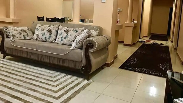 A living room with a sofa, a patterned rug, and a hallway leading to another room. - Just Home (Zanzibar Town)