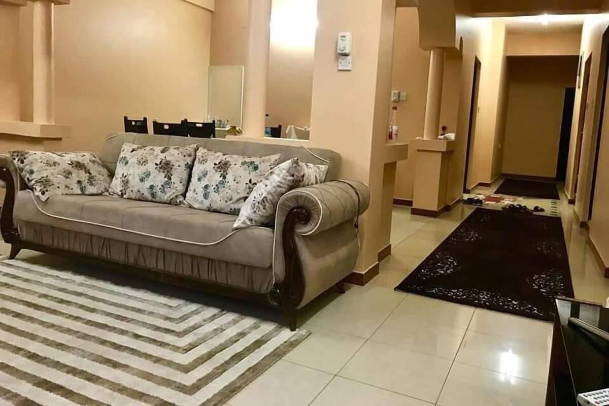 Een woonkamer met een bank, een kamerbreed tapijt en een gang naar een andere kamer.