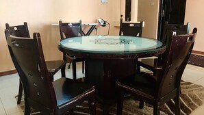 A round glass table with a floral design surrounded by six dark wooden chairs. - Just Home (Zanzibar Town)