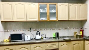 A kitchen with beige cabinets, a microwave, a kettle, and a toaster on the countertop. - Just Home (Zanzibar Town)