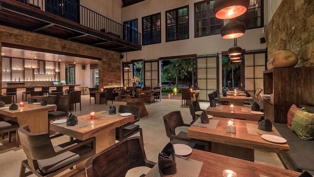 A spacious restaurant with high ceilings, wooden tables, and hanging pendant lights. - Kemangi Bed & Breakfast (Kuta)