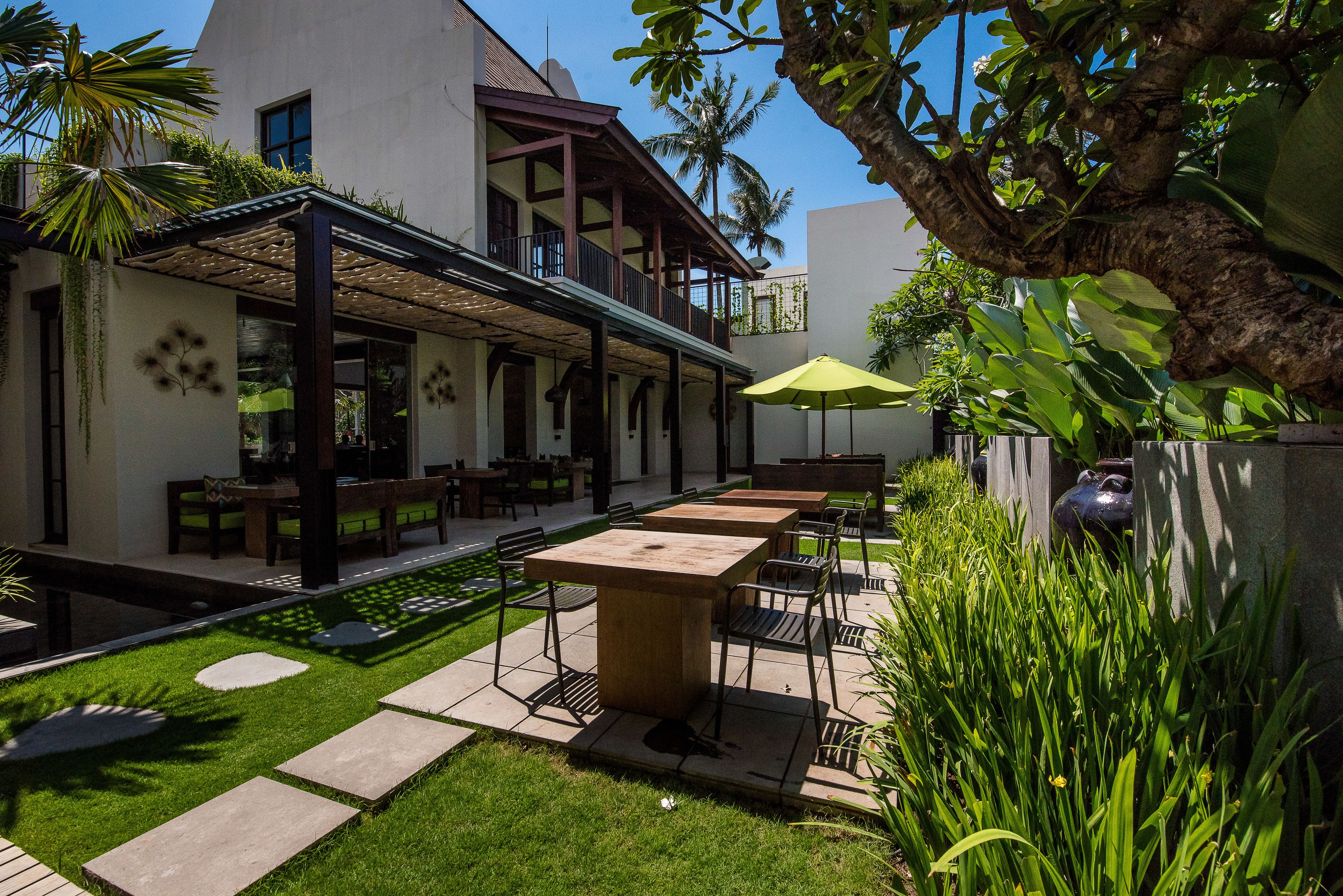 An outdoor patio area with tables and chairs, a covered seating area, and a well-maintained lawn.