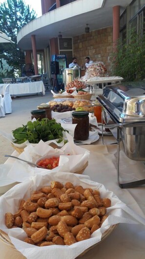 Un buffet en plein air proposant une variété d’aliments, notamment des noix, des fruits et un barbecue.