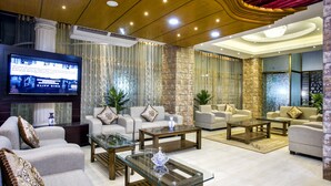 A modern living room with sofas, coffee tables, and a flat-screen TV. - White Palace Hotel (Dhaka)