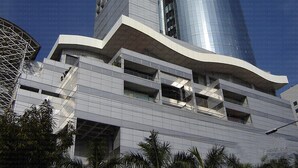 A modern building with a curved facade, multiple balconies, and a cylindrical glass tower. - White Palace Hotel (Dhaka)
