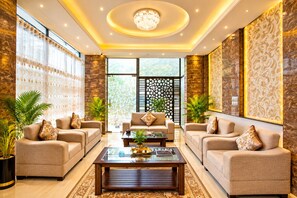 A spacious living room with two sofas, a coffee table, and decorative plants. - White Palace Hotel (Dhaka)