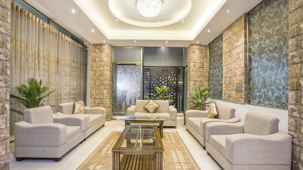 A modern living room with two sofas, a glass coffee table, and decorative plants. - White Palace Hotel (Dhaka)
