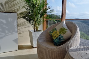 Relax in a peaceful space with a wicker armchair and a potted plant by the window.
