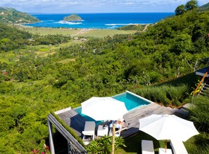 A pool area with a view of the ocean and hills.