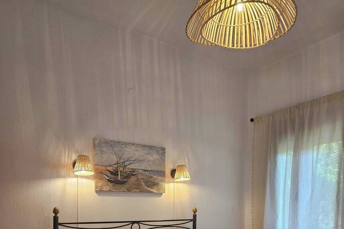 A neatly made bed with white and yellow pillows, a painting above it, and a lamp on either side.