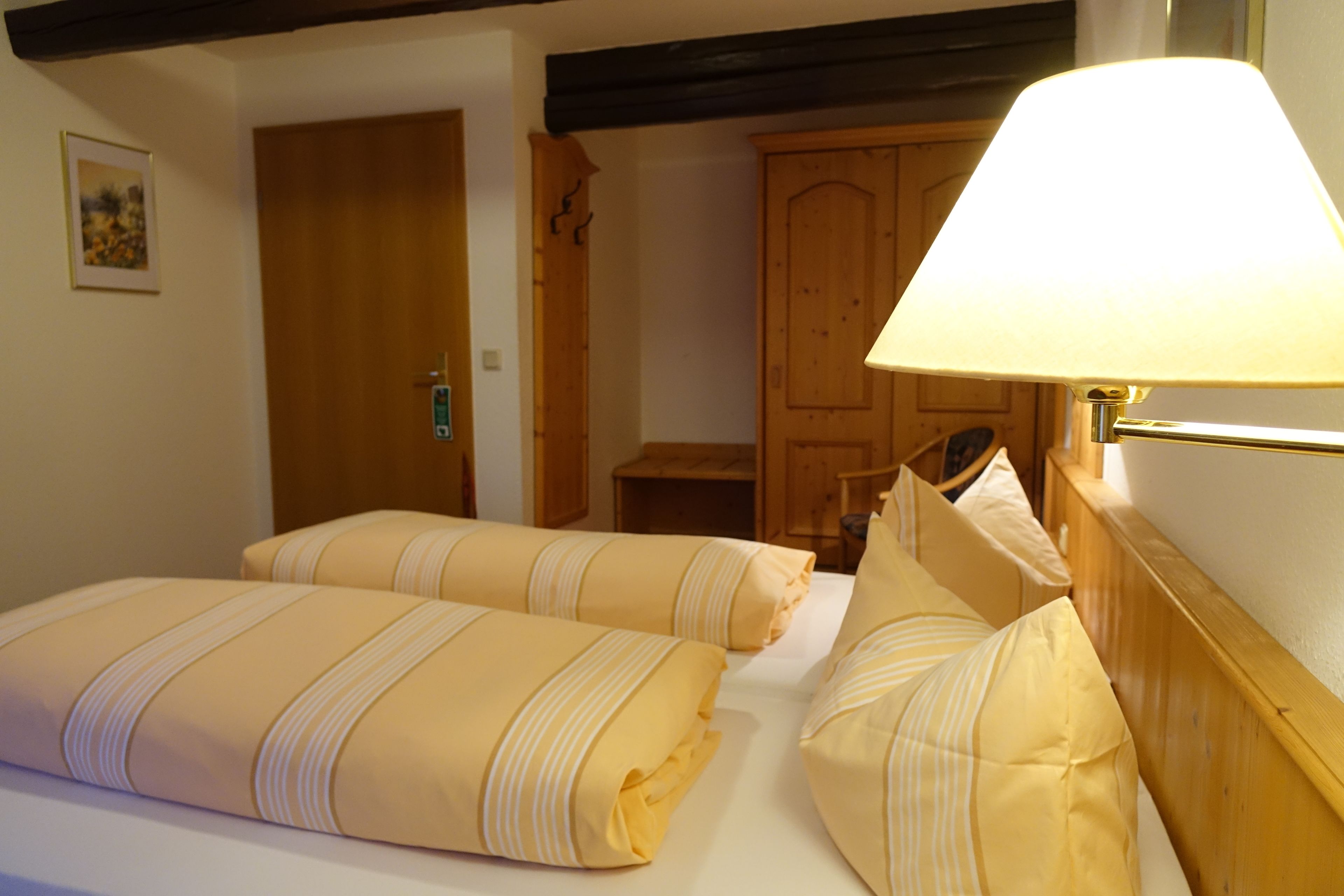 Ein Hotelzimmer mit zwei Betten, einem Holzschrank und einer Nachttischlampe.