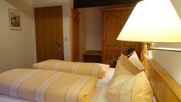 Ein Hotelzimmer mit zwei Betten, einem Holzschrank und einer Nachttischlampe.