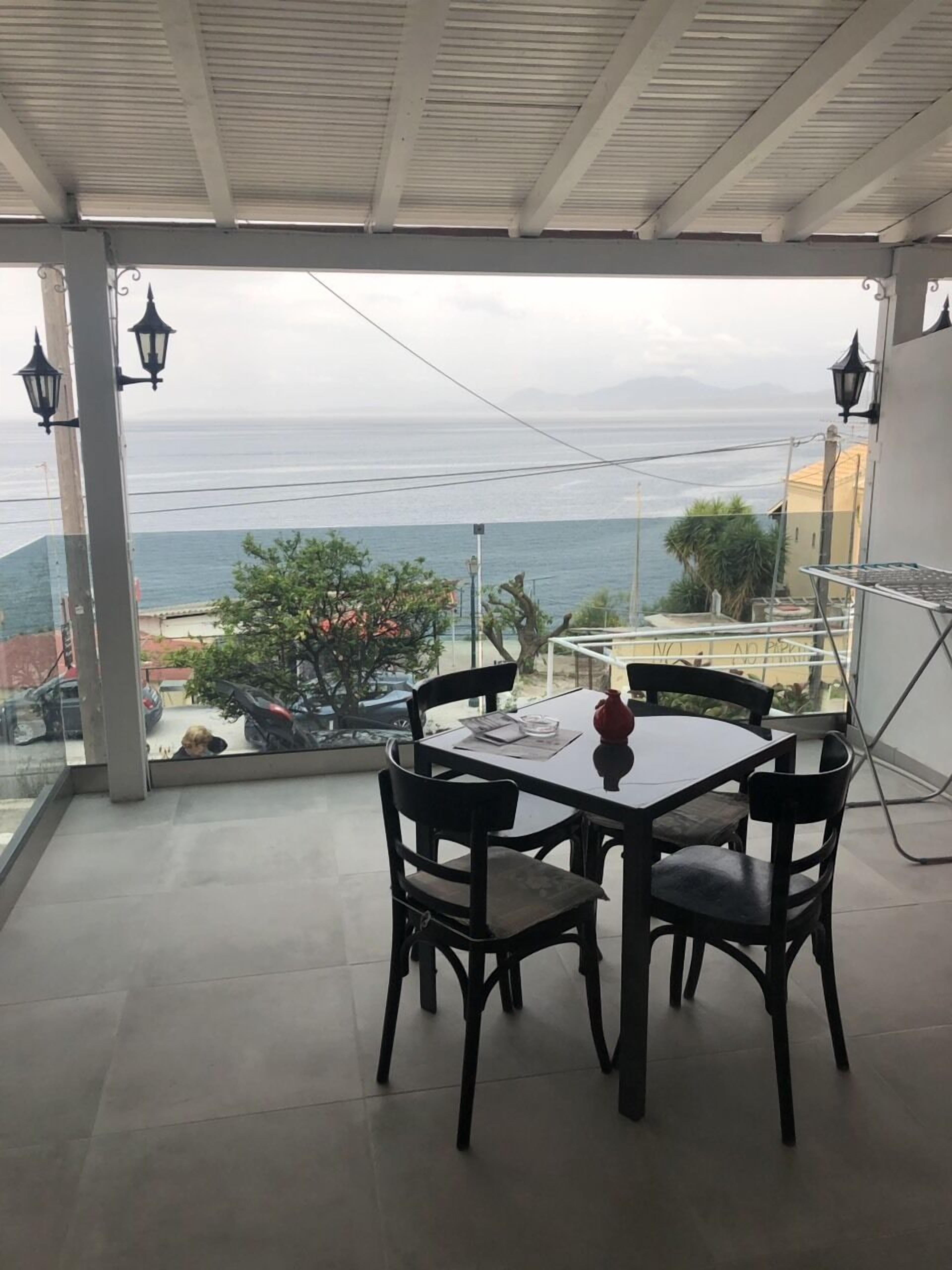 Un balcón con mesa y sillas, con vistas a la costa y un cielo despejado.
