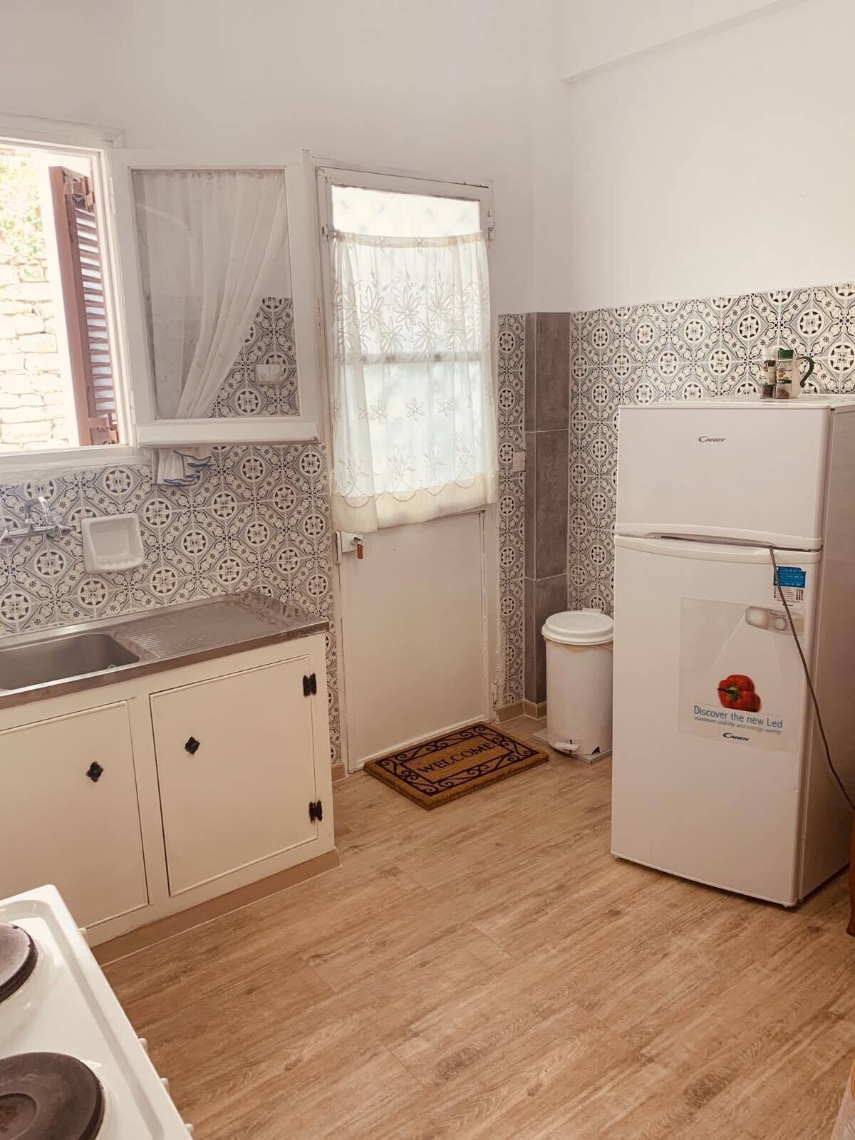 A compact kitchen with a sink, a stove, a refrigerator, and patterned walls.