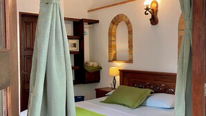 Un dormitorio con cama de madera, cortinas verdes, una lámpara de pared y estante con diseño de ladrillo.