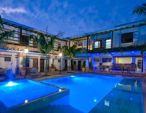 A pool area with a clear blue pool, lounge chairs, and a bar area with seating. - Camali Hotel (Santa Marta)