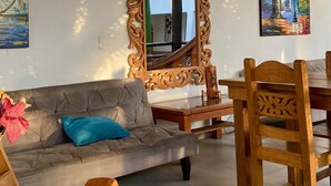 Una sala de estar acogedora con techo de madera, un espejo grande y decorativo, y un comedor con mobiliario de madera.