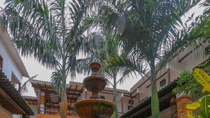 Un patio con una fuente central, rodeado de escalones de ladrillo y abundante vegetación.