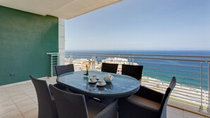 A balcony with a glass table and wicker chairs, overlooking a coastal view. - Ocean Front LUX Apartment inc Pool, Upmarket Area (Sliema)