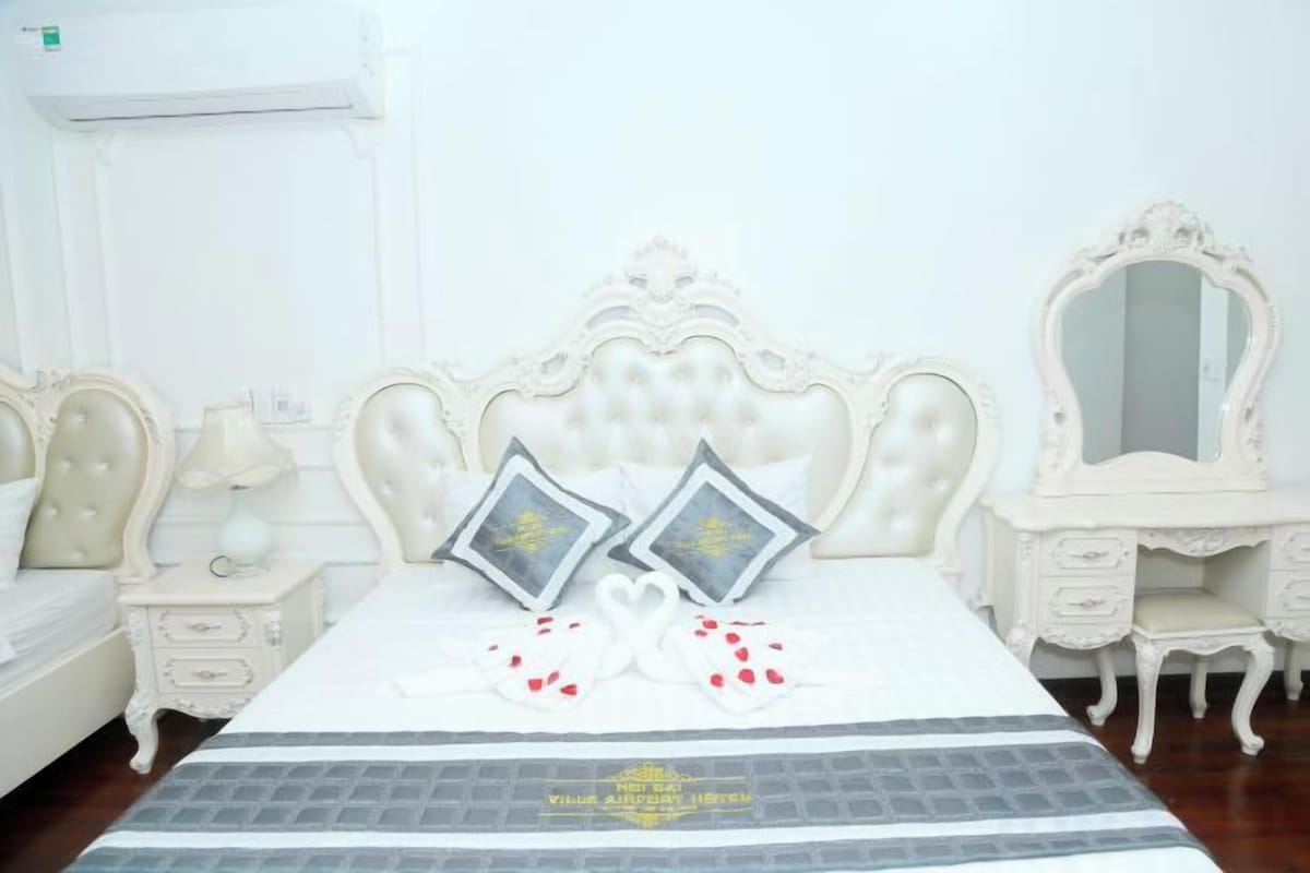 A bedroom with a large bed, two nightstands, a dresser, and a mirror.