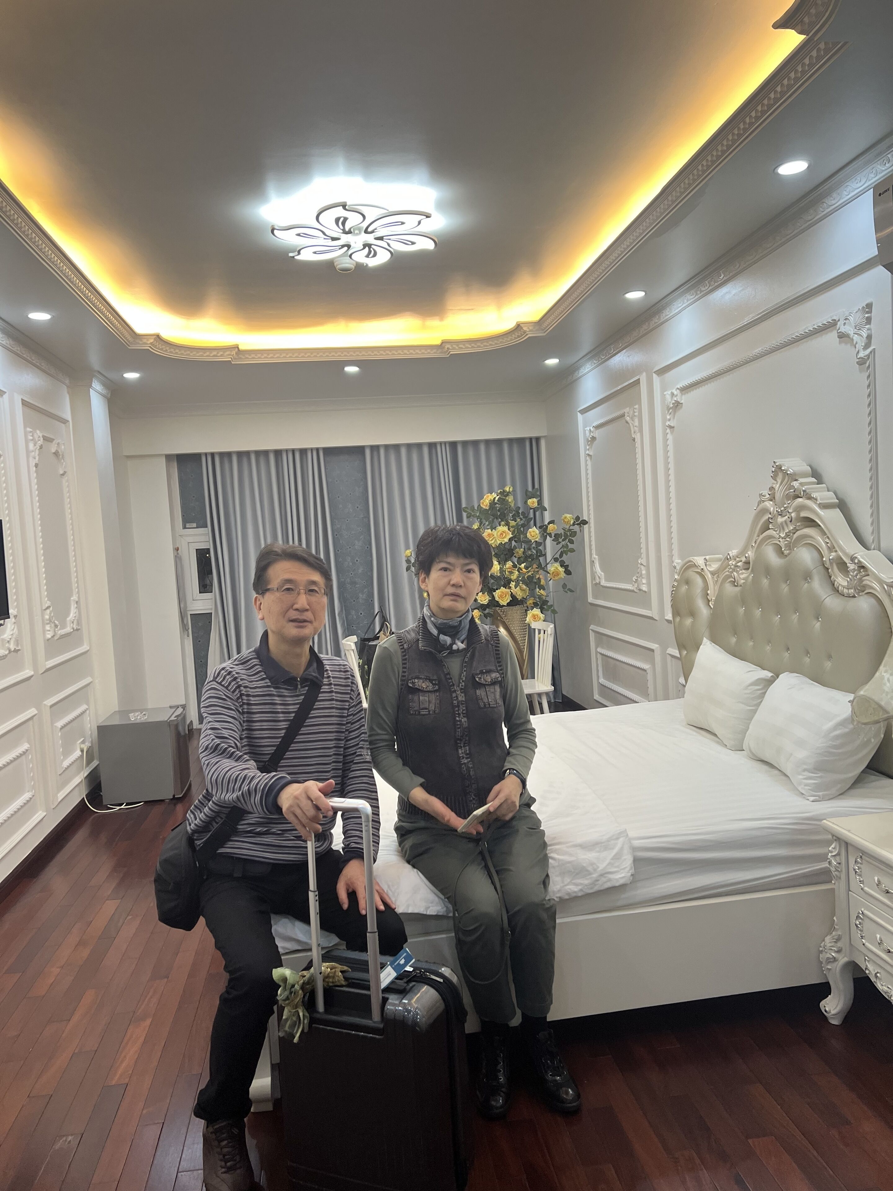 Una camera d'hotel con un letto grande, un comodino e un lampadario moderno.