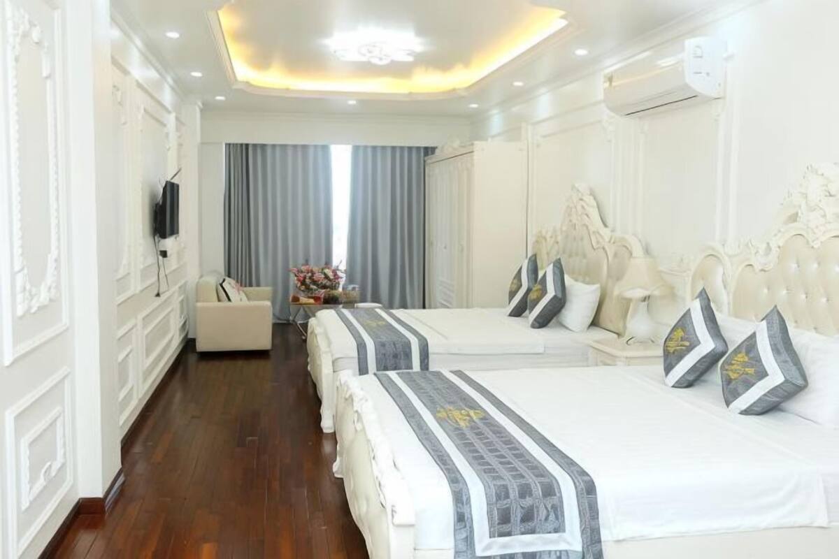 Une chambre d’hôtel avec deux lits, une télévision, un bureau et une fenêtre avec des rideaux.