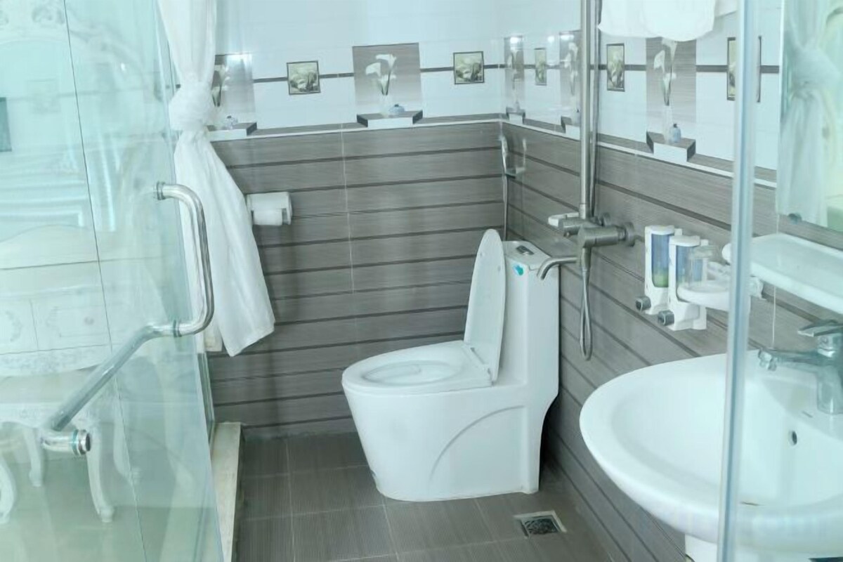A modern bathroom with a toilet, sink, and glass shower enclosure.