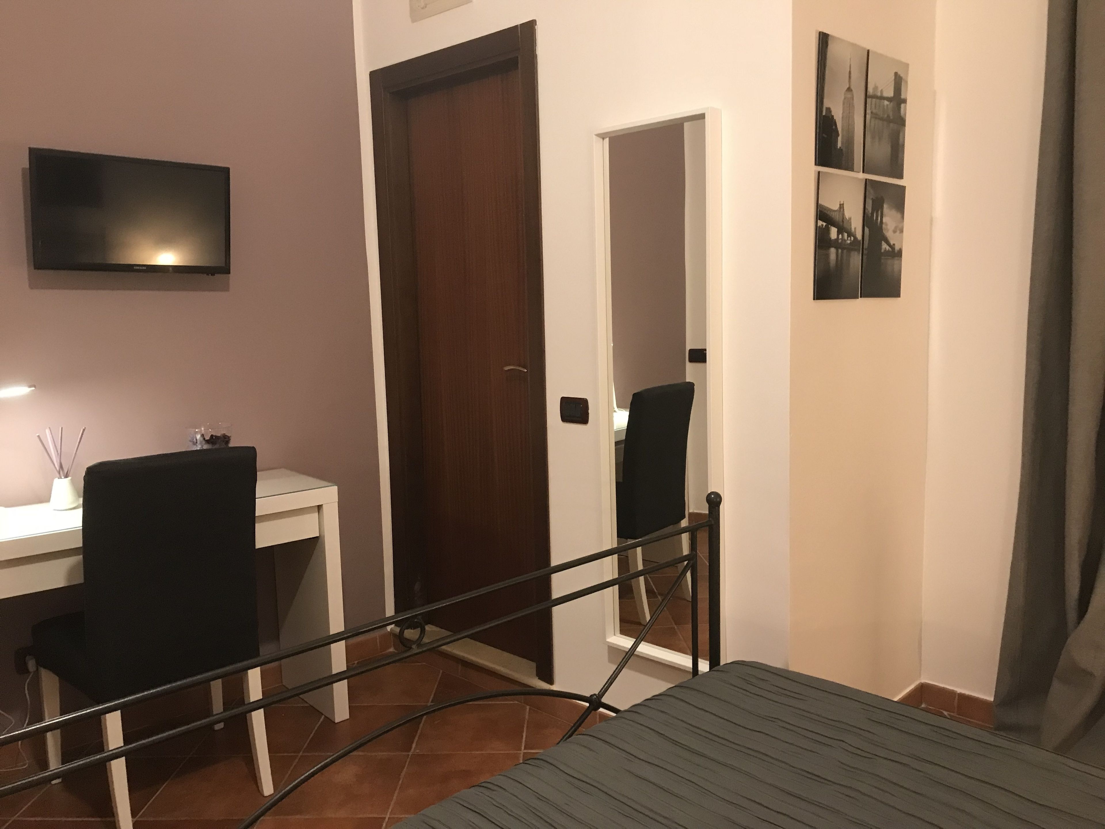 Une chambre à coucher avec un lit, un bureau, deux chaises, une télévision et une porte.
