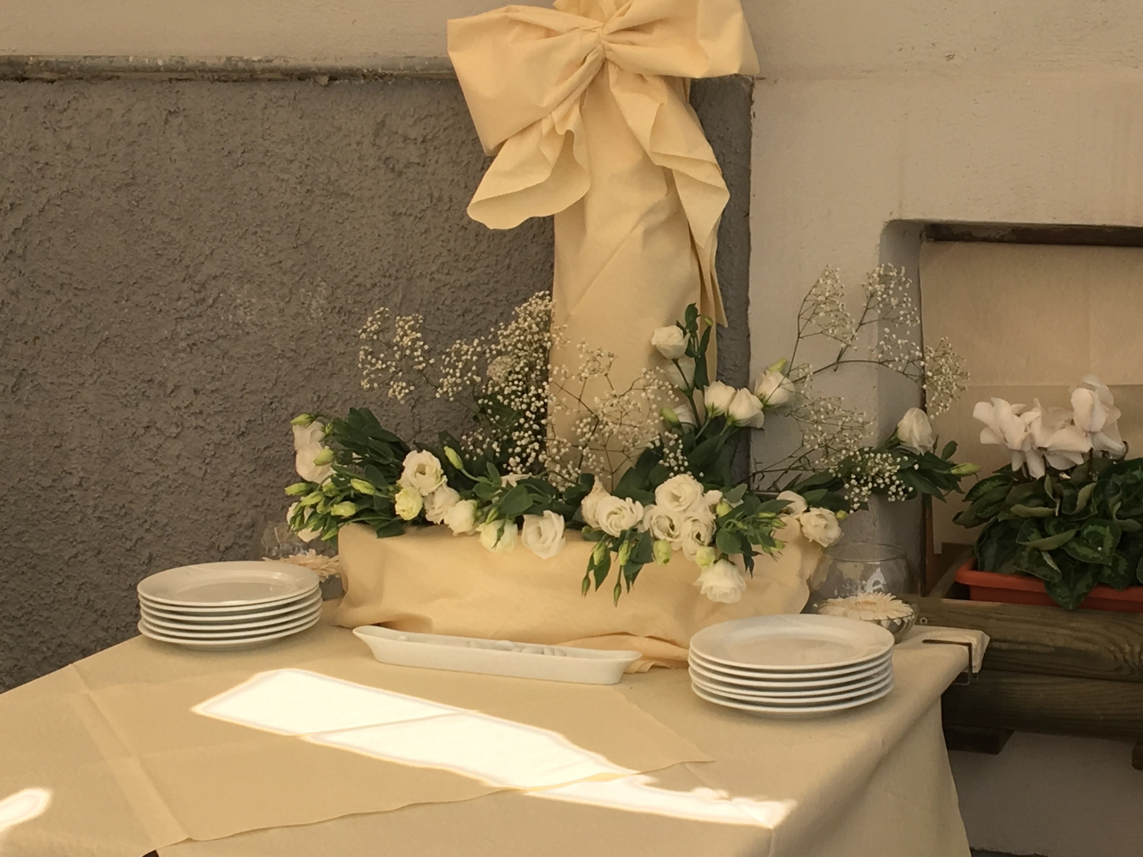 Une table dressée avec des assiettes, une serviette et un bouquet de fleurs blanches.