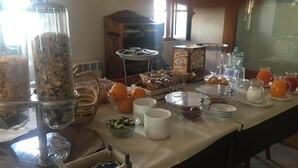 A buffet table with various food items and containers, including bowls of fruits, a container of cereal, and several pitchers of beverages. - Locanda Al Castello (Peschici)