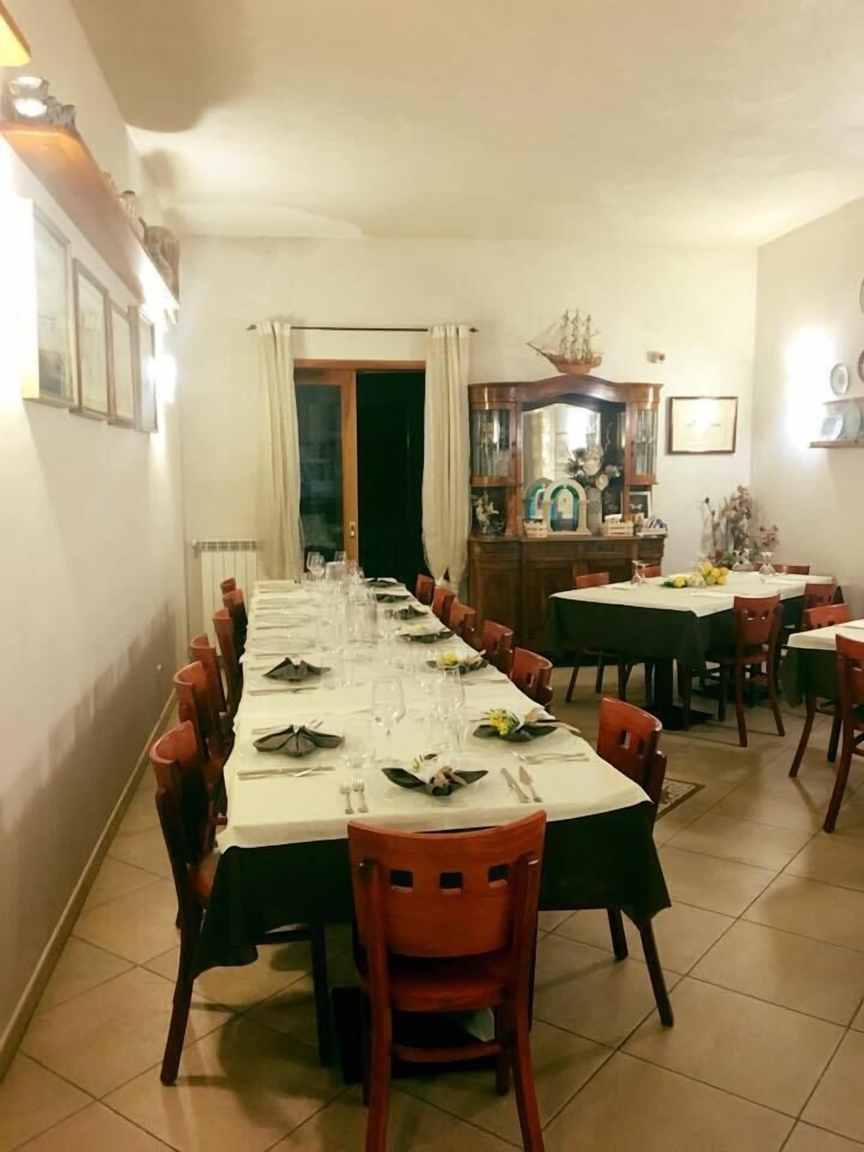 A dining area with a long table set for a meal, surrounded by chairs.