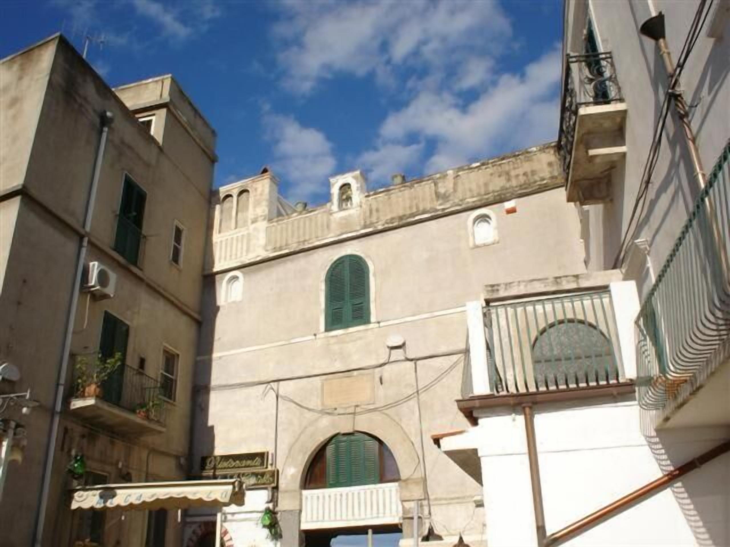Una calle estrecha con edificios que tienen ventanas de arco y balcones.