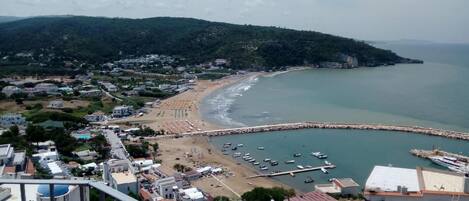 A coastal town with a beach, marina, and residential buildings.