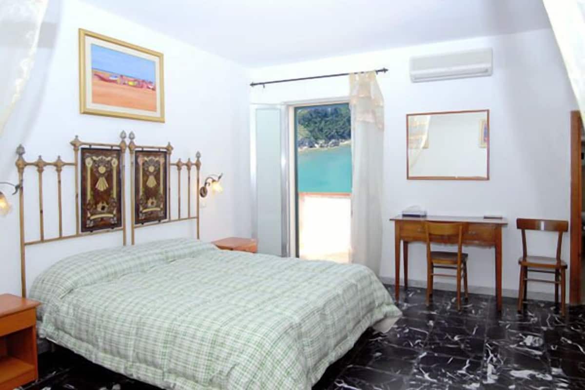 A bedroom with a bed, a desk, and a chair.