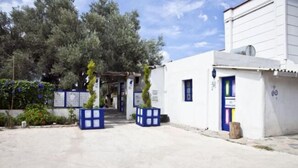 A building with a white exterior, a blue door, and a small attached structure. - Sahin Motel & Restaurant (Bodrum)