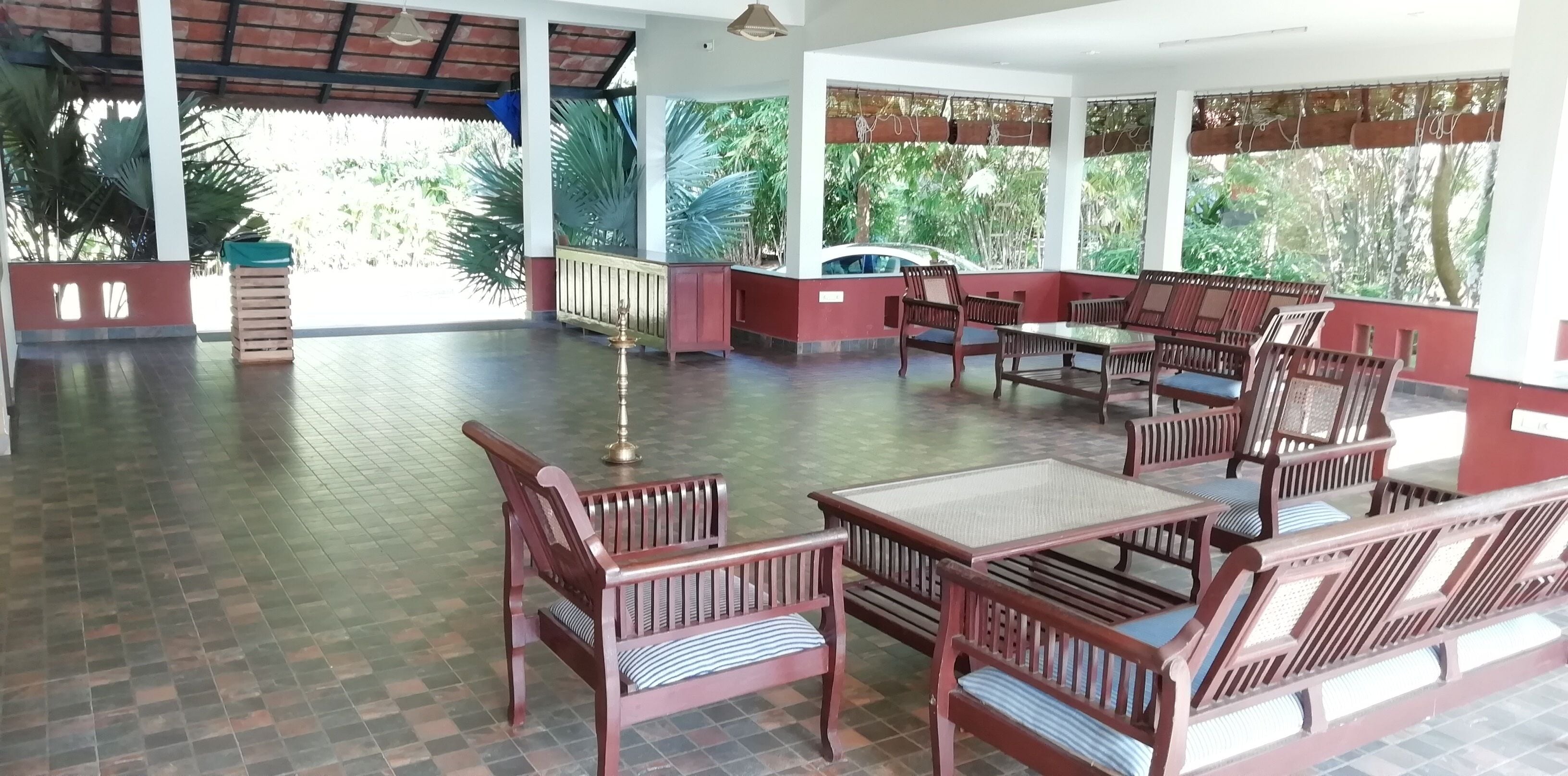 A covered outdoor seating area with wooden furniture and a tiled floor.