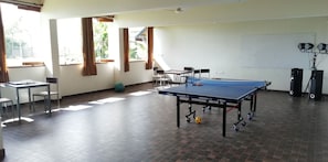 A room with a ping pong table, chairs, a small table with a bottle, and a green exercise ball. - Vistara Resort (Sulthan Bathery)