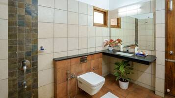 Un baño con ducha, inodoro, lavabo y una planta en maceta.