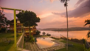 A swimming pool with a view of a lake and mountains at sunset. - Vistara Resort (Sulthan Bathery)