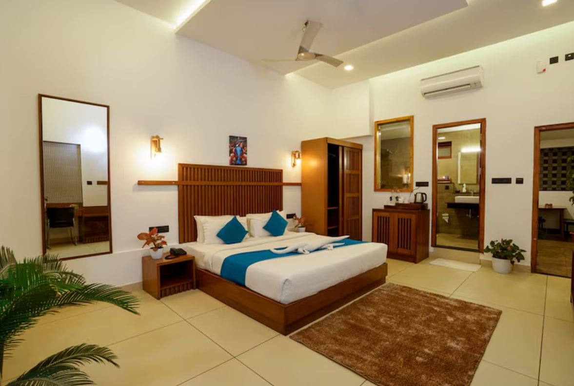 A modern bedroom with a large bed, bedside tables, a wardrobe, and a bathroom with a mirror.