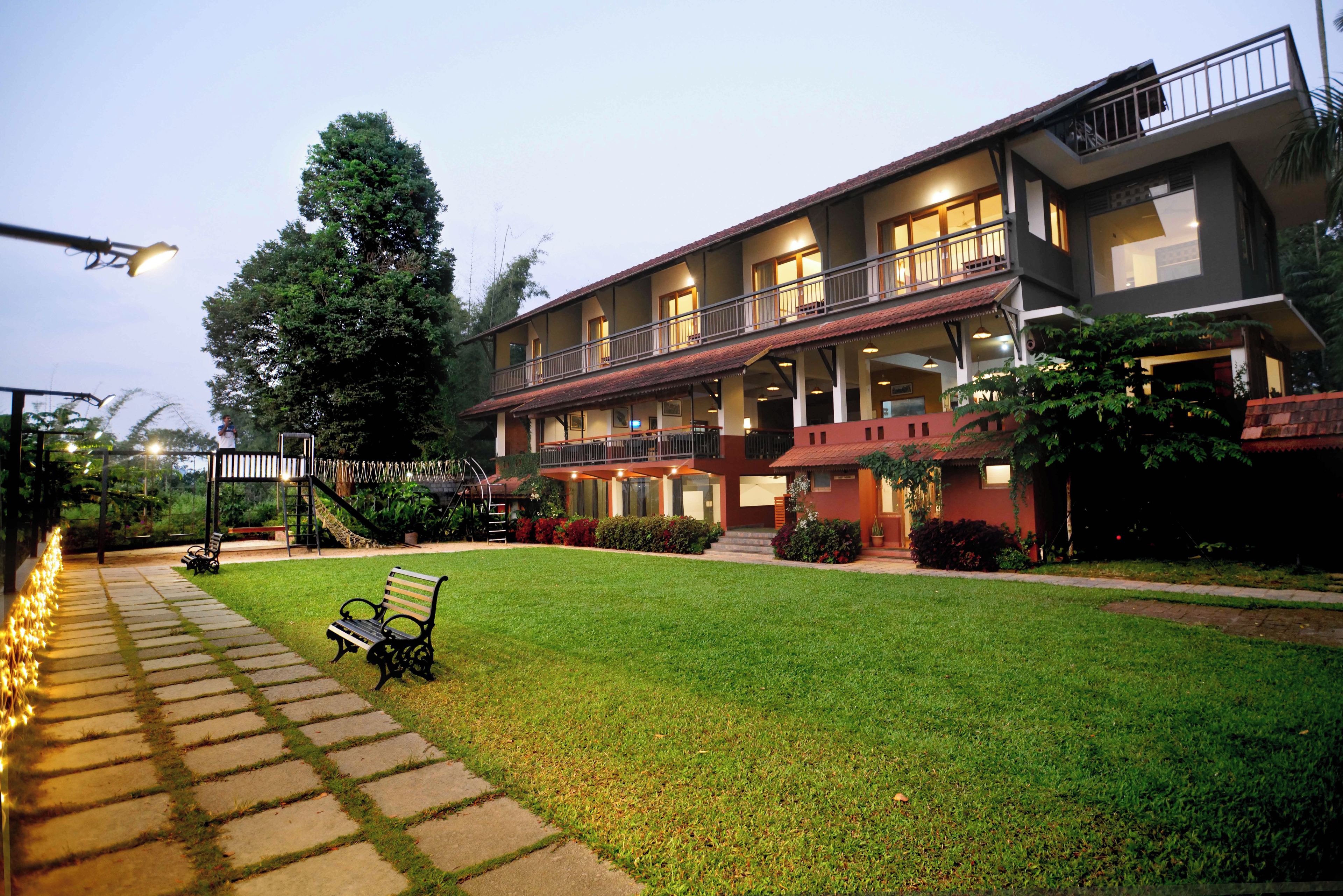 Um hotel com estrutura em dois andares, área de estar coberta ao ar livre e um gramado bem cuidado.
