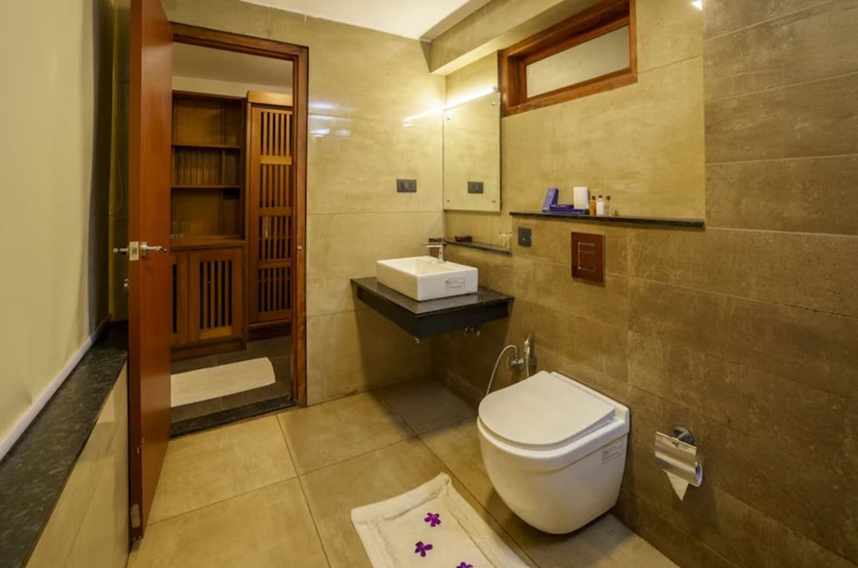 A bathroom with a toilet, sink, and mirror.