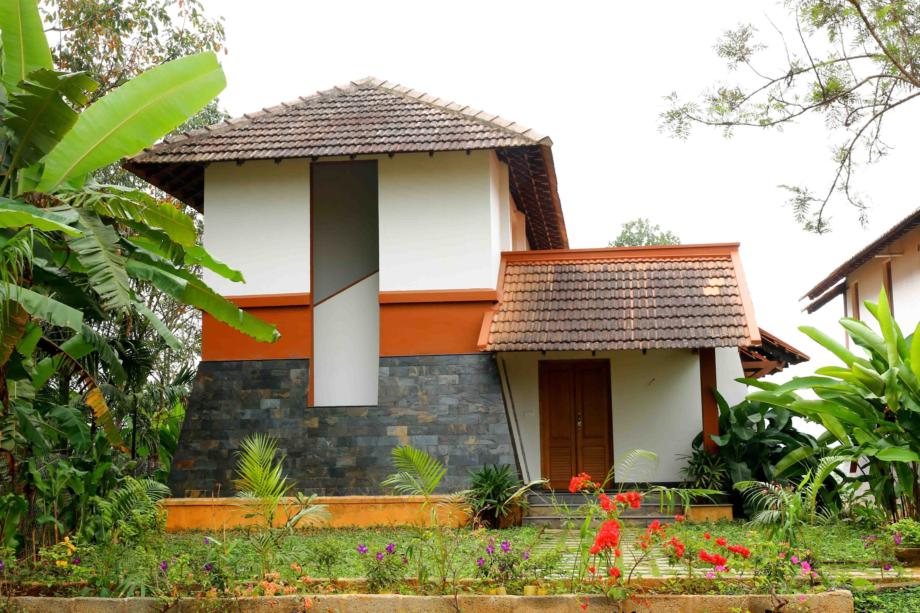 A two-story building with a tiled roof, a stone facade, and a wooden door.