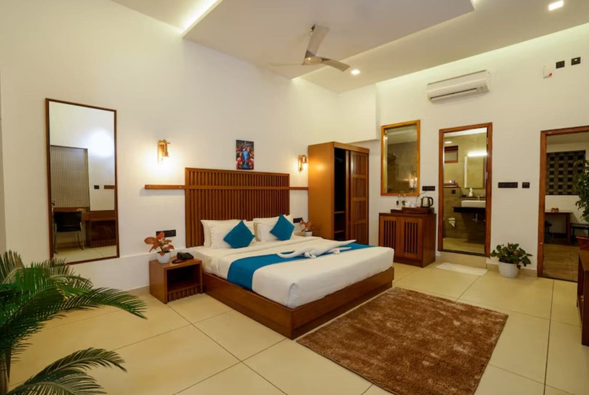 Habitación de hotel con cama, mesitas de noche, armario, espejo y ventilador de techo.