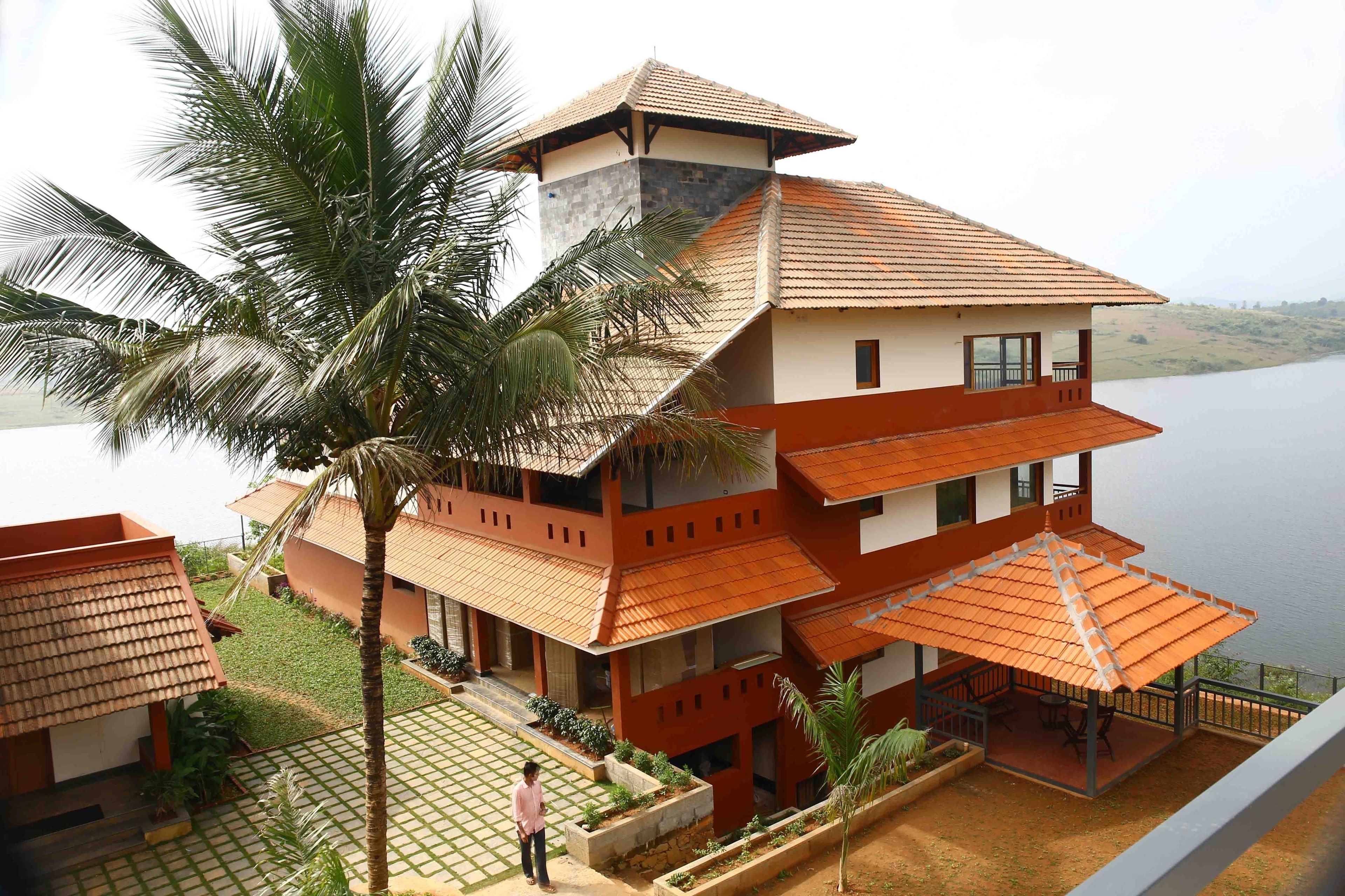 A multi-story building with a tiled roof, a balcony, and a view of a body of water.