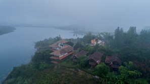 A coastal village with traditional houses, a body of water, and a hilly landscape. - Vistara Resort (Sulthan Bathery)